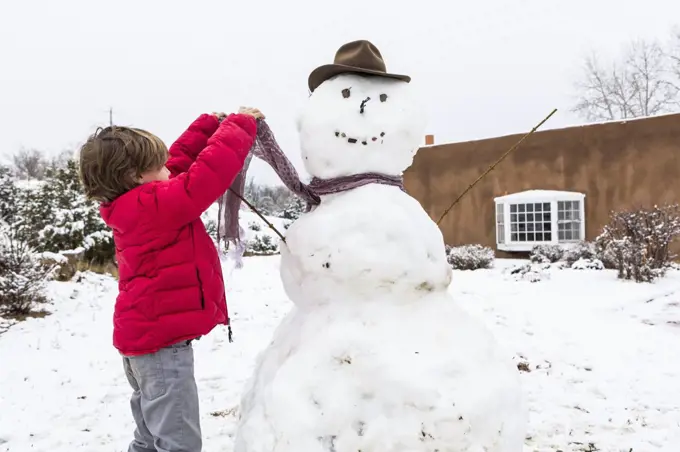 A young boy building a snowman