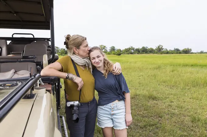 mother photographing with teen daughter near safari vehicle, Botswana