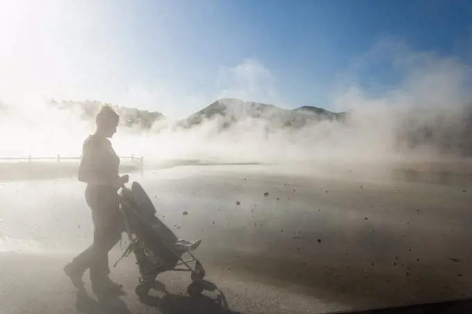 A woman and a child in a buggy in rising steam from thermal pools