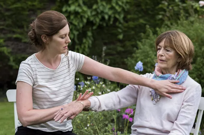 Reiki therapist with a client in a therapy session touching meridian points on the body.