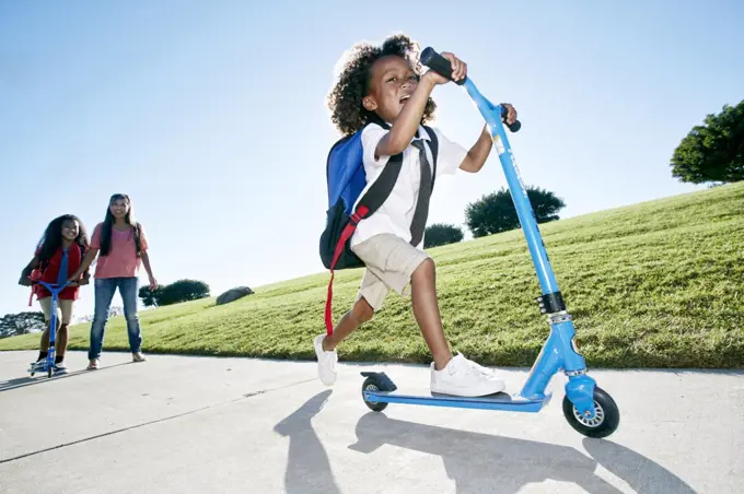 Six year old boy on a scooter, followed by his sister