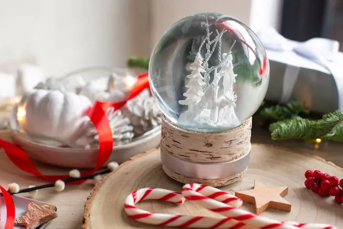 Christmas decorations, a snow globe and presents and star shaped biscuits. 