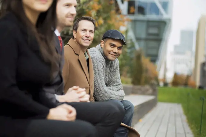 City life. A group of people on the go, keeping in contact, sitting on a bench. Men and women.New York city, USA