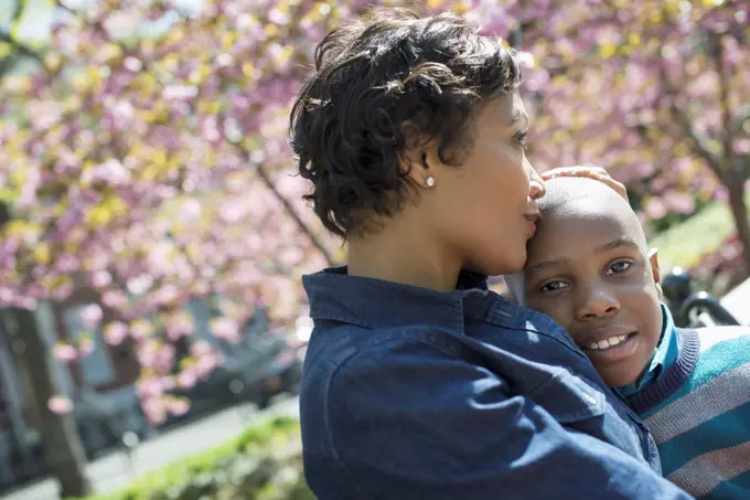 A New York city park in the spring. Sunshine and cherry blossom. A mother and son spending time together. New York city, USA