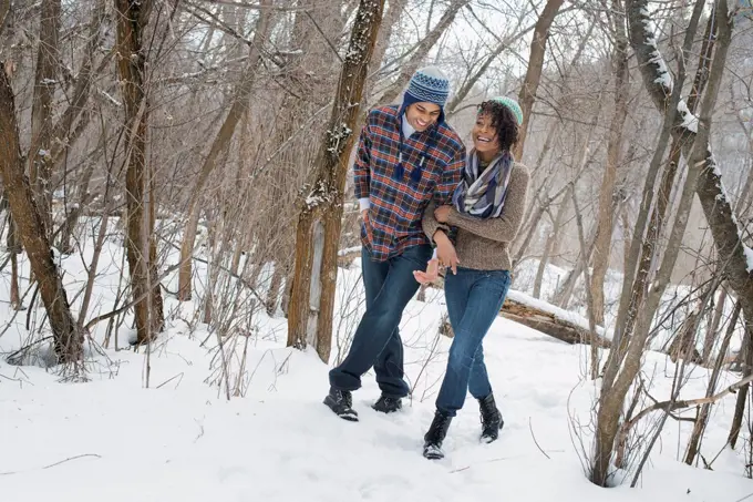 Winter scenery with snow on the ground. A couple arm in arm walking through the woods.  Provo, Utah, USA