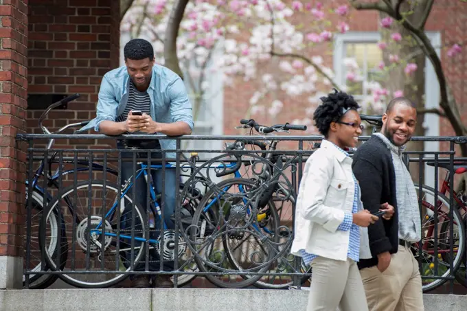 A bicycle rack with locked bicycles, a man texting and a couple walking by. New York City, USA