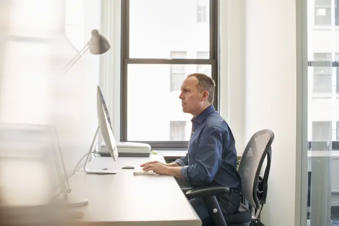 A businessman seated at his desk working at a computer.