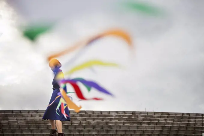 An artist during a performance moving a line of flags or streamers.