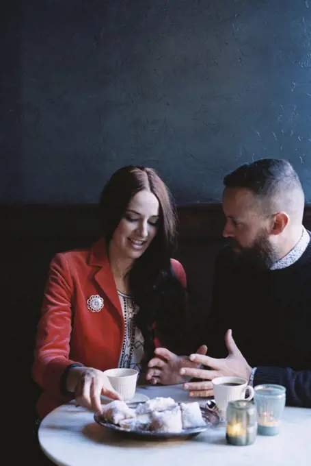 A couple seated side by side at a cafe table.