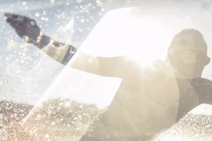 A swimmer in a wet suit running into the water, making a splash.