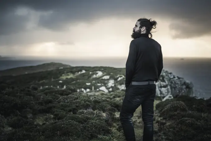 A man standing looking out over the landscape at sunset.