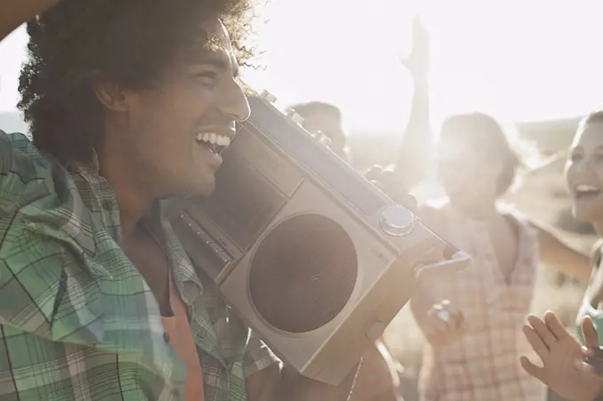 Group of young people, men and women walking on the open road with a boombox.