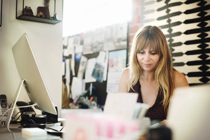 Woman sitting in an office at a desk with a computer, working.