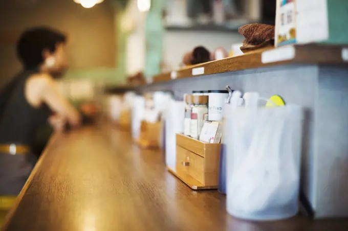 The ramen noodle shop. A long counter with dishes, condiments and forks.