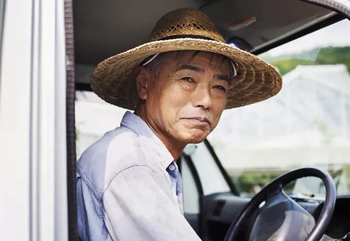 A man in a hat sitting in the driving seat of a truck.