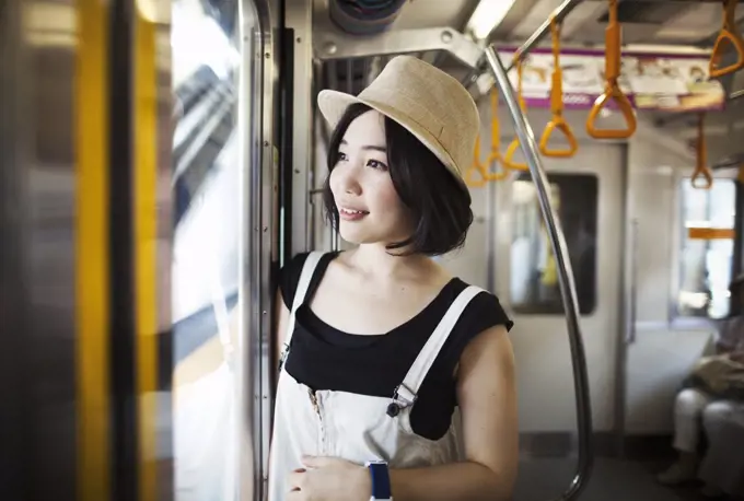 Young woman wearing a hat traveling on a train.