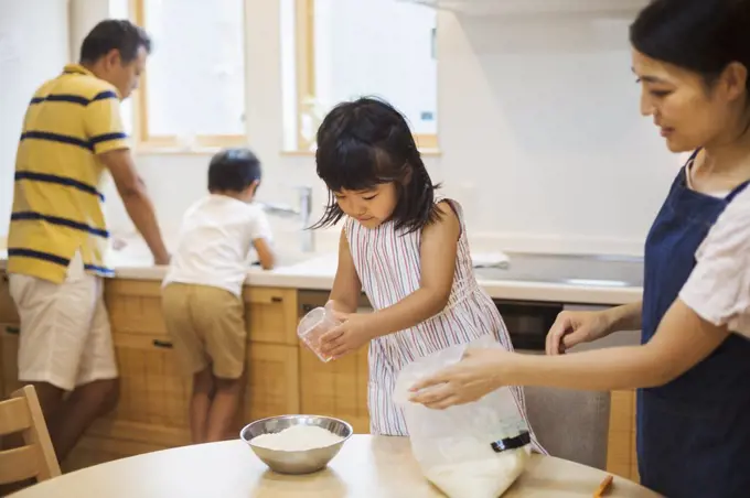 Family home. Two parents and two children preparing a meal.