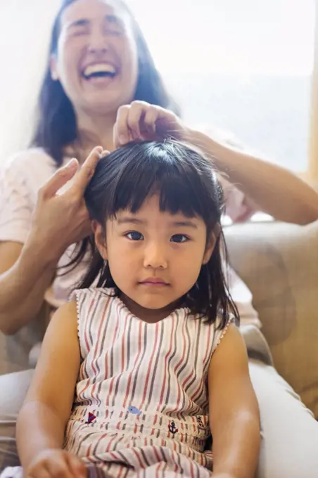 Family home. A mother combing her daughter's hair.