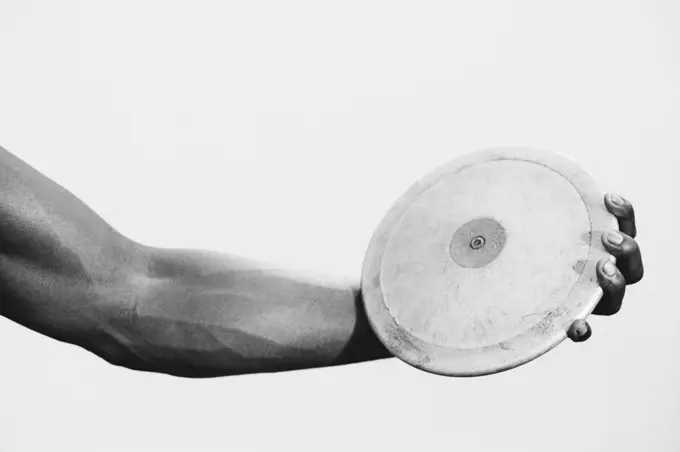 A female track and field athlete holding a discus in her hand.