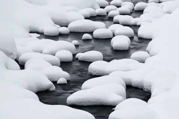 Close up of riverbed with snow-covered rocks in winter.