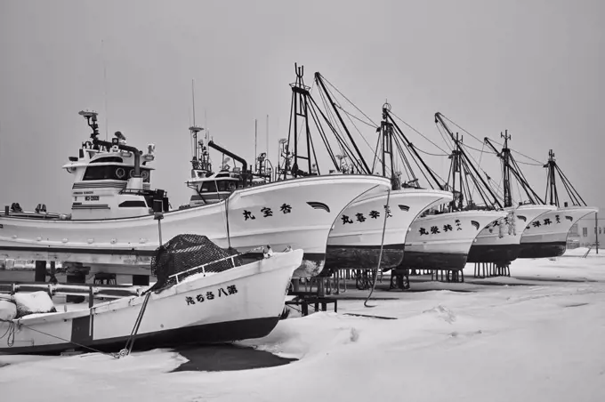 Row of fishing boats on dry platforms in winter.