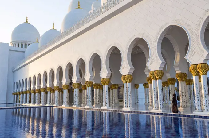 White colonnade of Sheikh Zayed Mosque and blue fountain, Abu Dhabi, United Arab Emirates.