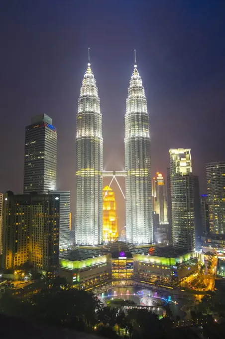 Cityscape of Kuala Lumpur in the evening, with the illuminated Petronas Towers in the distance, Malaysia.