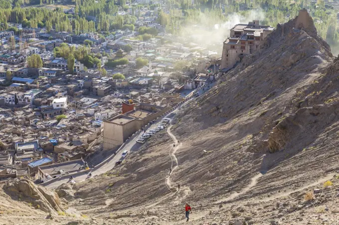 High angle view of town with man climbing up dusty mountain slope.