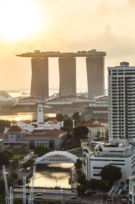 Cityscape with skyscrapers at sunrise, three towers connected by roof terrace in the distance.