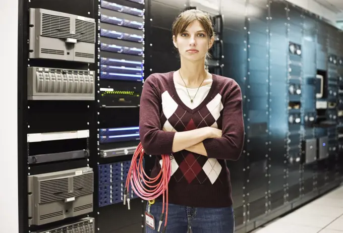 Portrait of female technician working in a large computer server room.