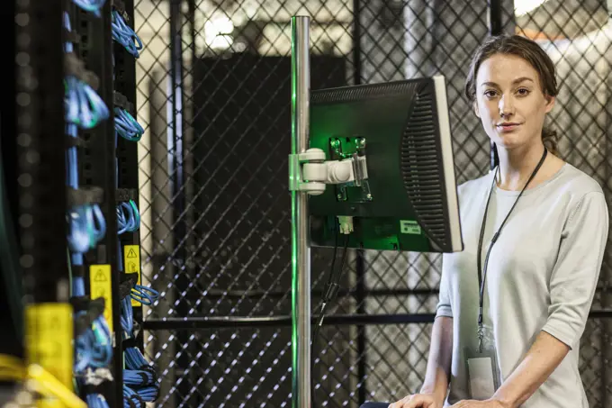 Caucasian woman technician working on computer servers in a server farm.