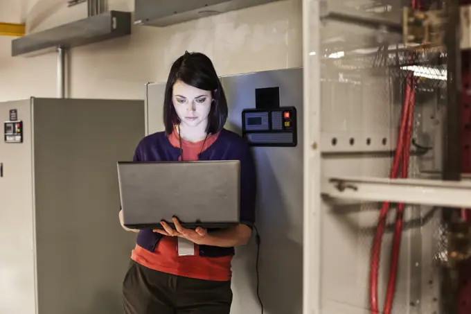 Caucasian woman technician working on computer servers in a server farm.