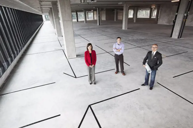 Asian architect with Caucasian man and woman business people in a new raw business space.