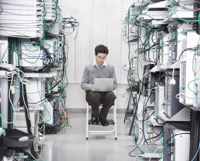 Caucasian male technician working on computer servers in a computer server farm.