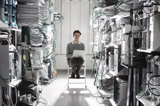 Caucasian male technician working on computer servers in a computer server farm.