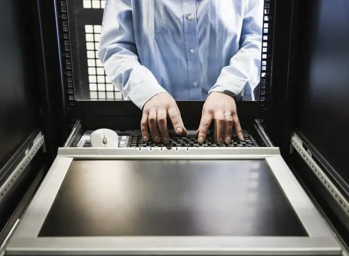 Closeup of a the hands of a technician working on data from a computer server farm.