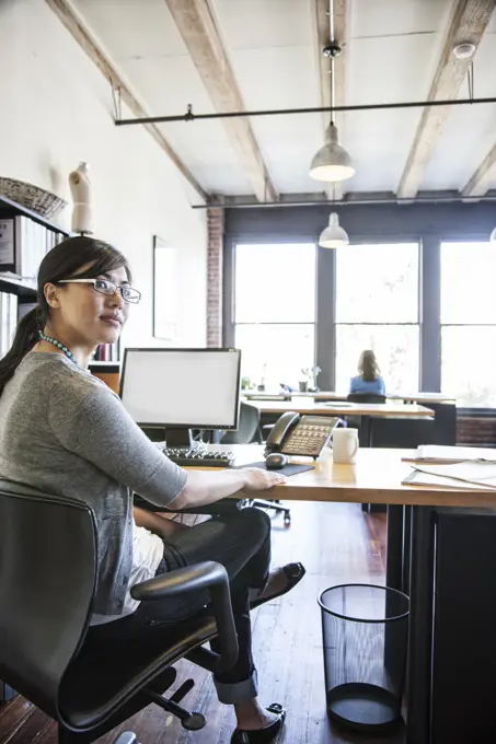 Asian woman working at her desk in a creative office.