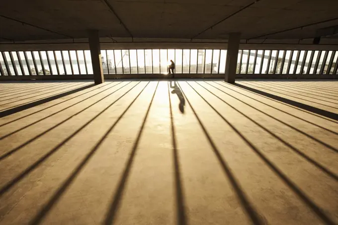 Businessman exploring new empty raw business space for a new office at sunset, sunlight streaming through the wall of glass.