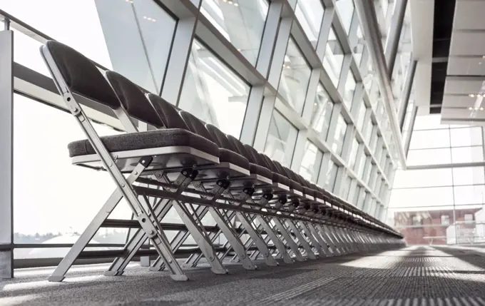 Chairs lined up against a window in a conference centre lobby area.