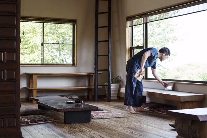 Japanese man standing in traditional Japanese house, preparing for tea ceremony.
