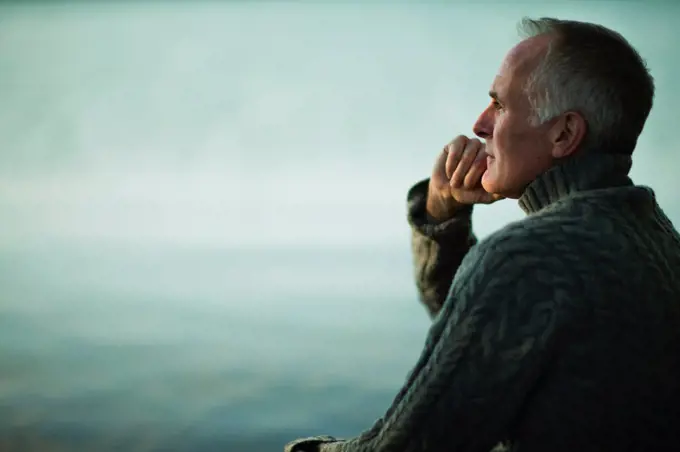 A mature man with grey hair, looking out over water, into the distance. Colorado, USA. 5/24/2012