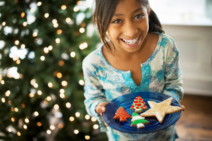 A young girl holding a plate of organic decorated Christmas cookies, Woodstock, New York, USA. 9/9/2012