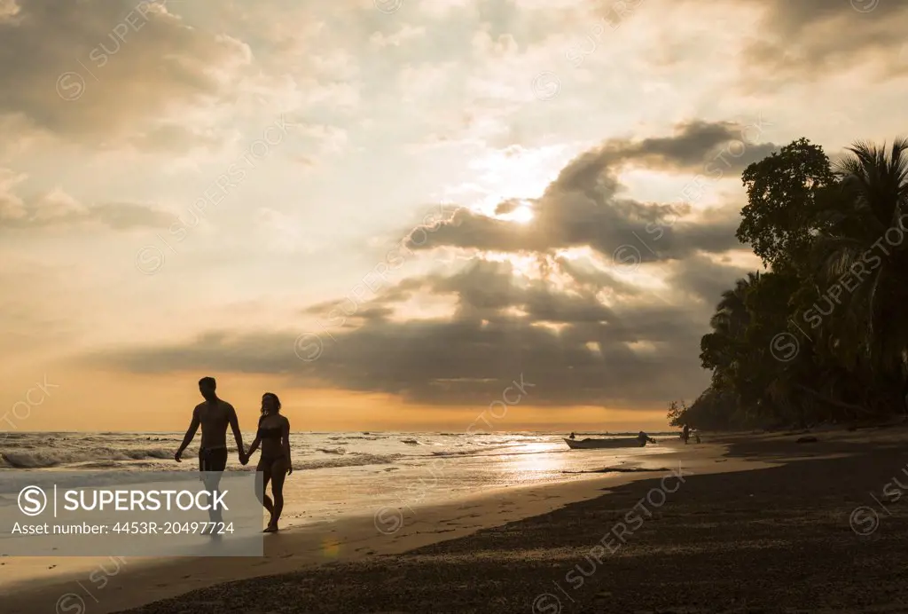 Couple walking on tropical beach at sunset