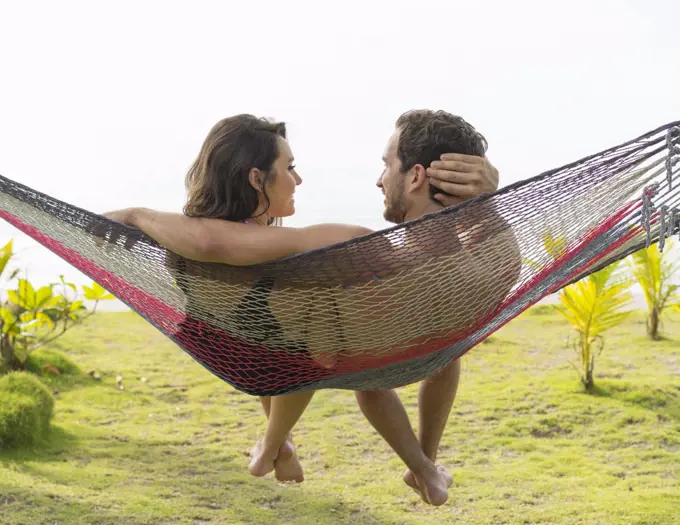 Couple sitting in hammock on beach