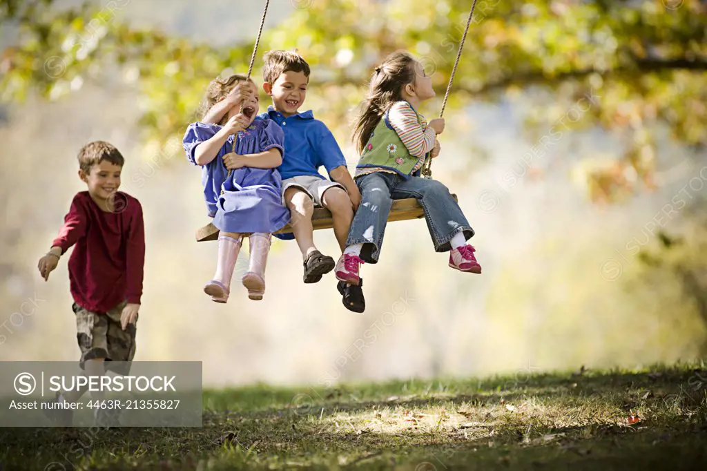 Boy pushing friends on a swing