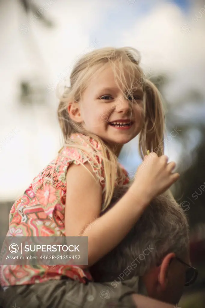 Young girl getting a shoulder ride from her dad.