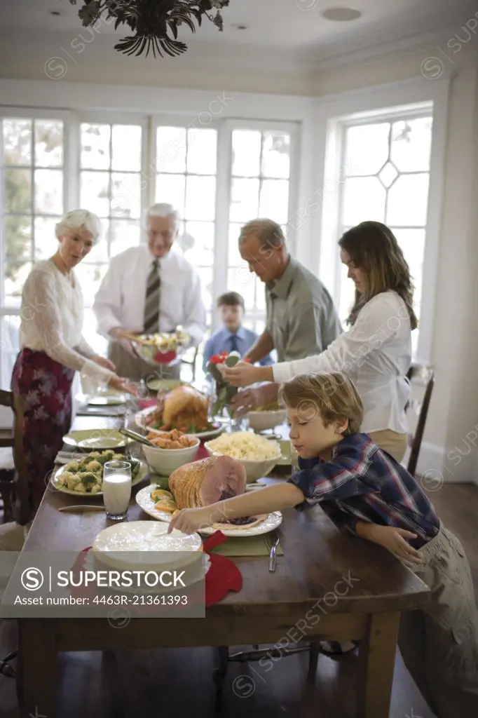 Boy touching a cake while having dinner with his extended family.