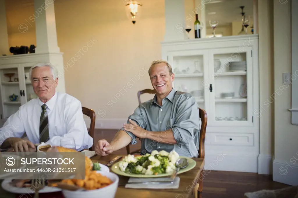 Portrait of two men sitting at a dining table for dinner.