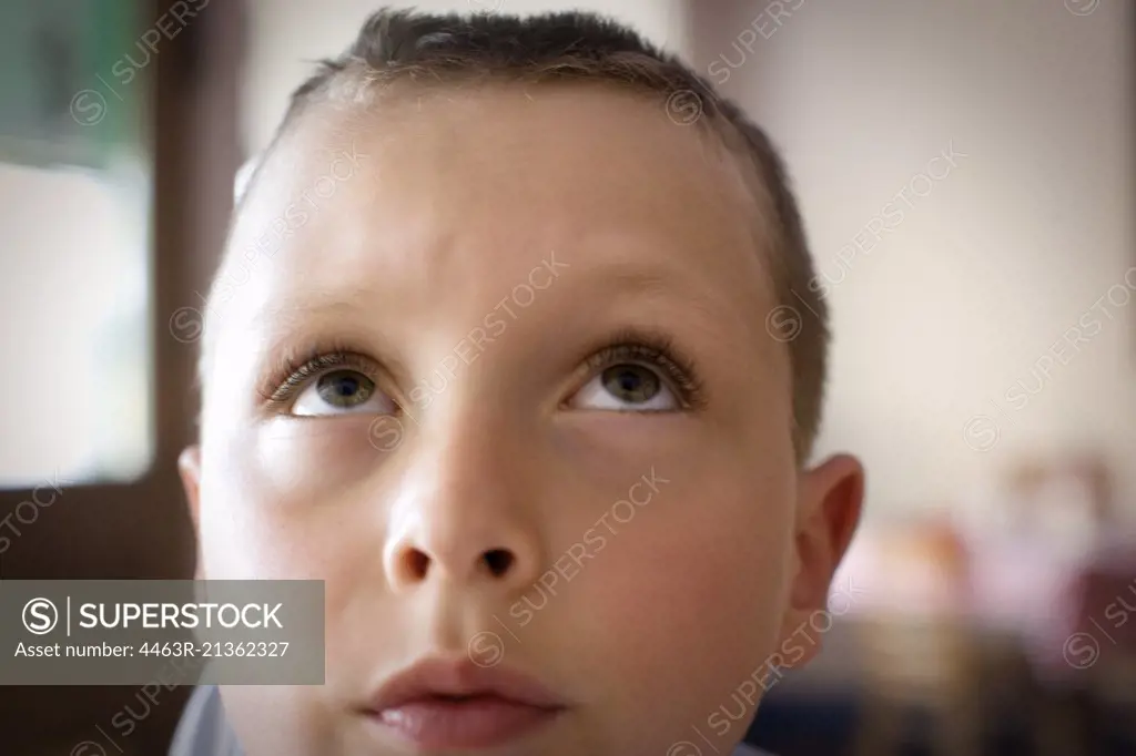 Boy sitting in a house looking up.