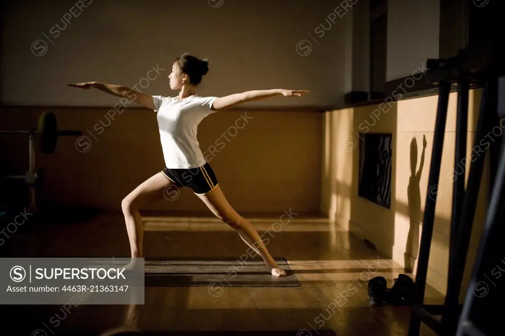 Teenage girl doing yoga in a gym.